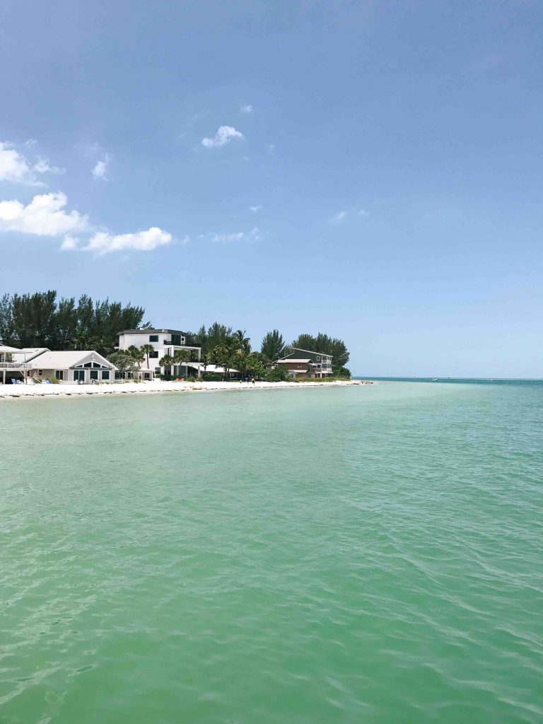 View of the pristine beaches on Anna Maria Island from Rod and Reel Pier with turquoise water and blue skies.