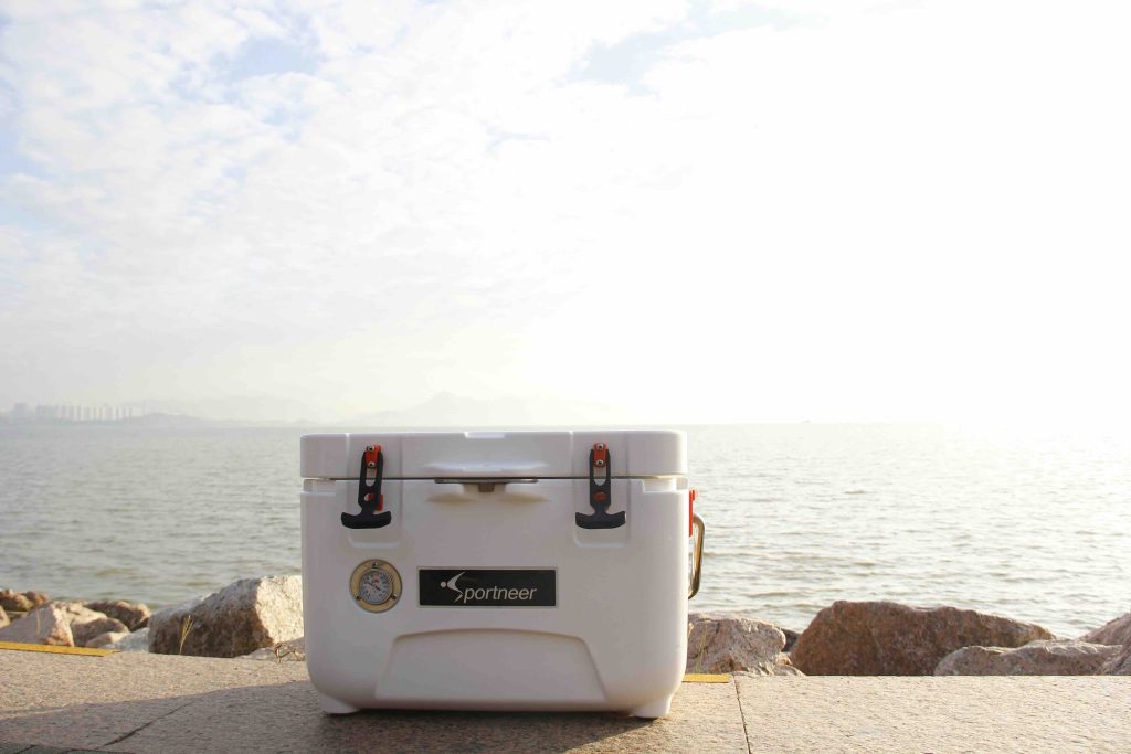 A cooler sitting in front of a lake with a blue sky in the background.