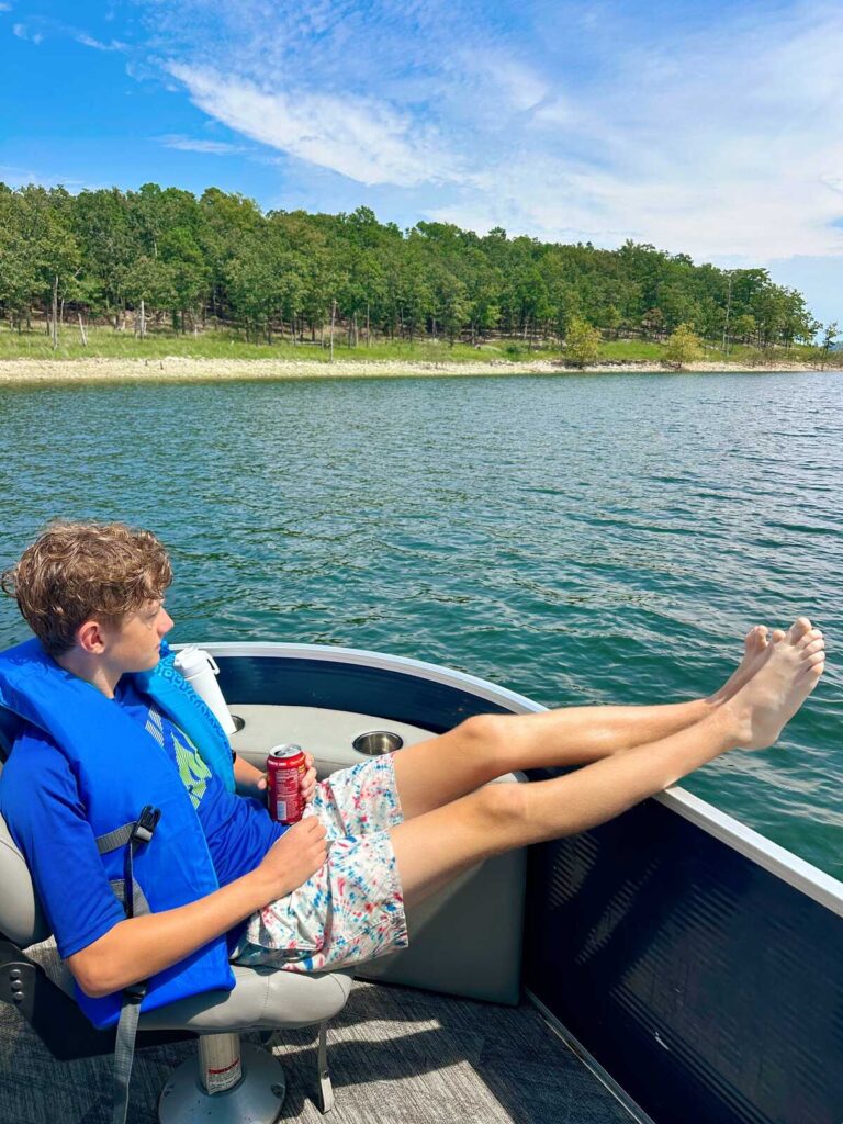 My son relaxing on a boat enjoying a view of the lake. He is holding a Poppi soda, one of our favorite lake day drinks.