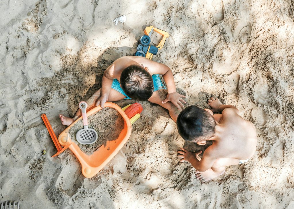 Toddlers playing in the sand at the beach.