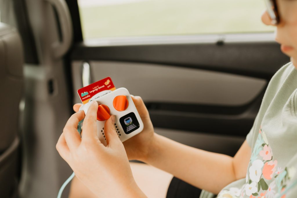 My daughter using a Yoto Mini on a road trip. These audiobook players have given us hours of calm and quiet on travel days!