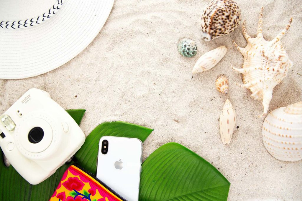 Beach photo with sand, camera, and seashells.