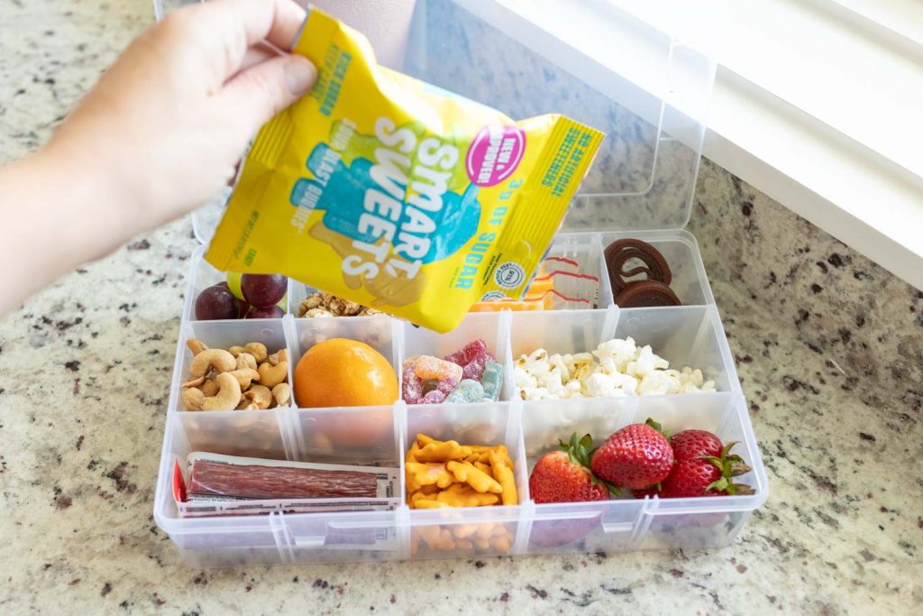 Pouring snacks into a snackle box with divided containers.
