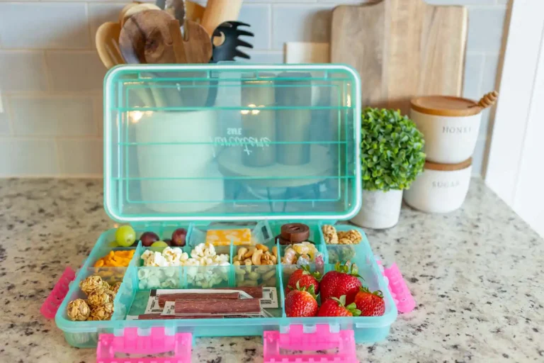 A teal-colored snackle box with a variety of snacks such as beef sticks, fruit, and nuts.