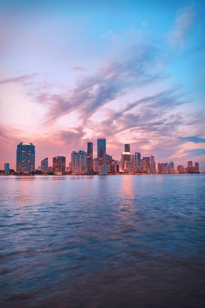 The Miami skyline at dusk with stunning pink and orange clouds and calm water.