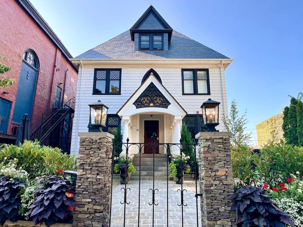 Beautiful white historic home in Newport, Rhode Island with an idyllic gate and flowers in front.