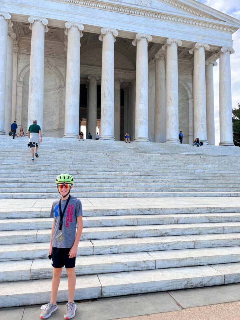 Our son standing outside the Jefferson Memorial with his bike helmet on during the Washington DC bike tour.