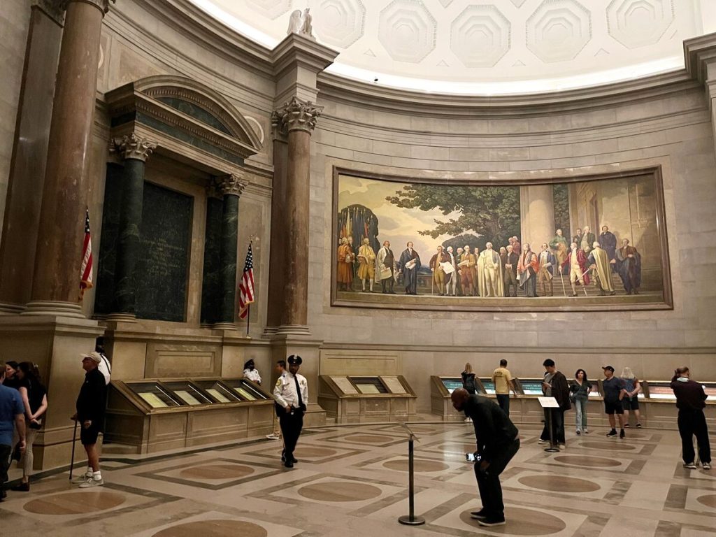 The area of the National Archives where the Declaration of Independence is displayed, surrounded by large historic pieces of art.