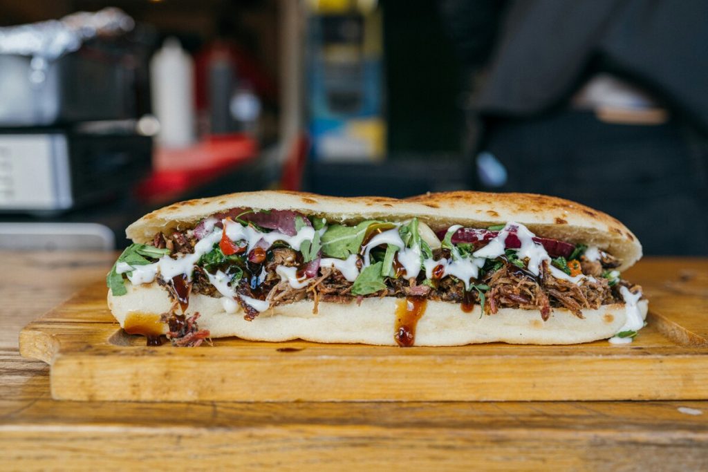 Delicious-looking barbecue sandwich sitting on a wood plank at a restaurant.