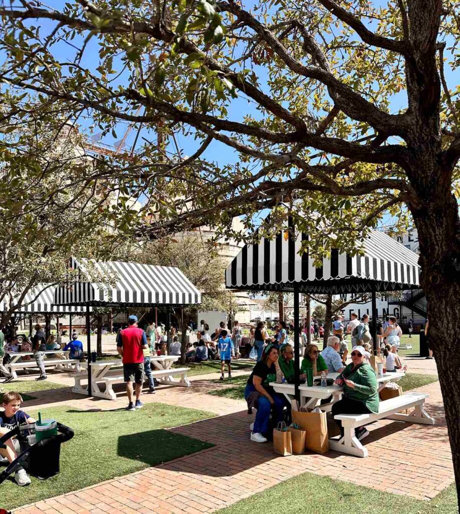 The food truck area featuring covered picnic tables with black and white striped awnings.