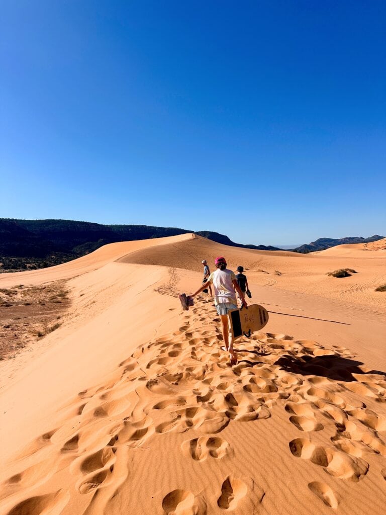 Our kids treking to the tallest dune carrying their sandboards and sleds.