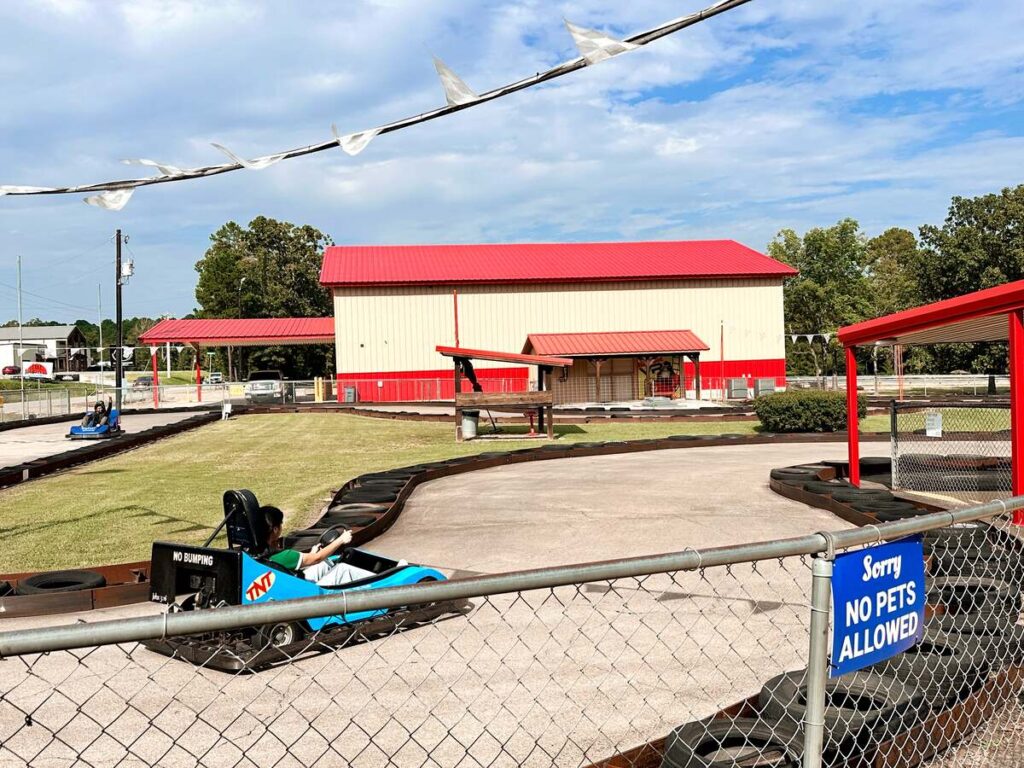 A go-kart track located in Broken Bow. A blue go-kart is racing around the track.