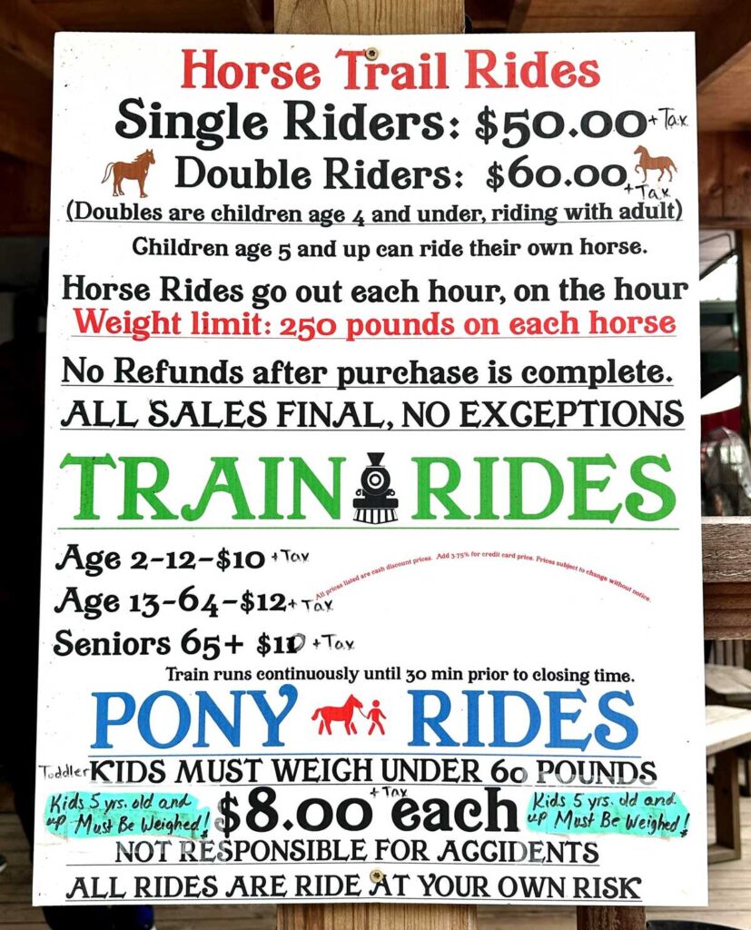 A photo of the sign at Beaver's Bend Depot that has details and prices about the train ride, pony rides, and trail rides.