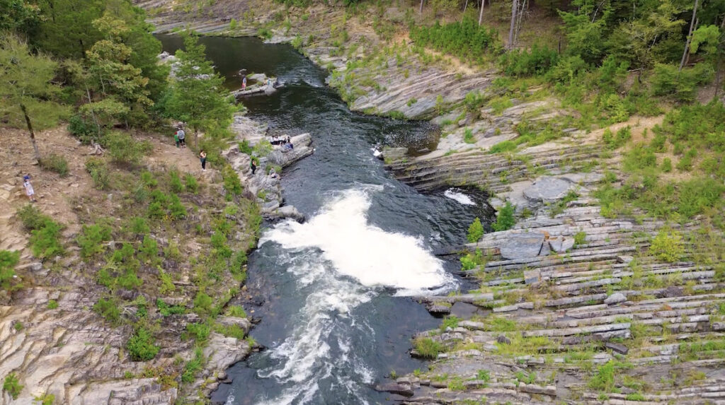 An aerial view of the Mountain Fork River along Friends Trail Loop. In the middle is a cascading waterfall.