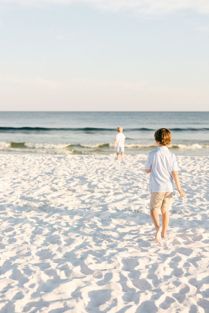 My kids walking through the white sand toward the ocean.