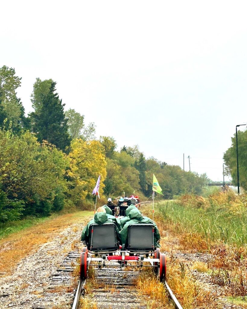Several railcars in a row pedaling down the tracks with trees on either side at Joyrails OKC.