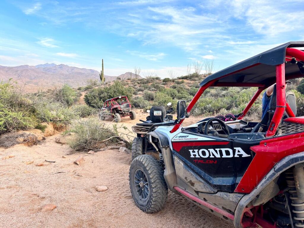 A red and black ATV on the right is facing beautiful desert landscape. This is where we stopped for snacks and drinks on the ATV tour.