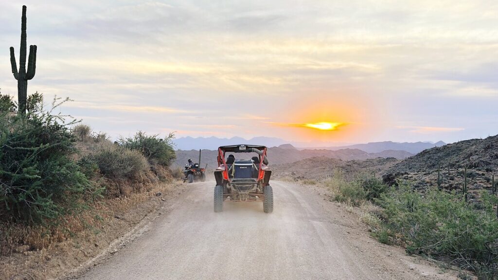 An ATV driving toward a sunset in the desert.