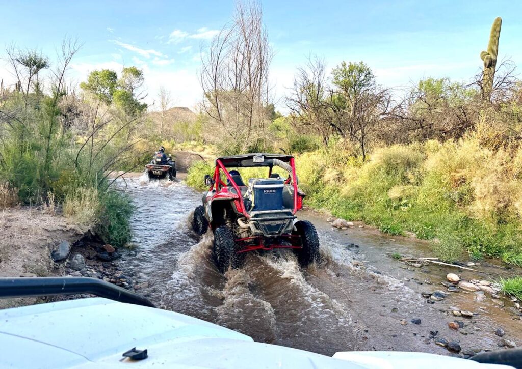 Austin driving our ATV through shallow water on an ATV tour in Scottsdale.